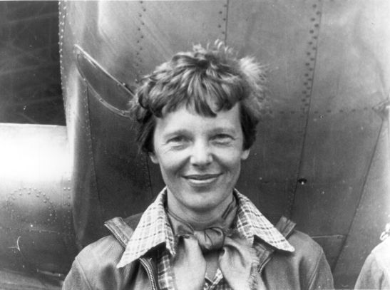 1200px-Amelia_Earhart_standing_under_nose_of_her_Lockheed_Model_10-E_Electra,_small